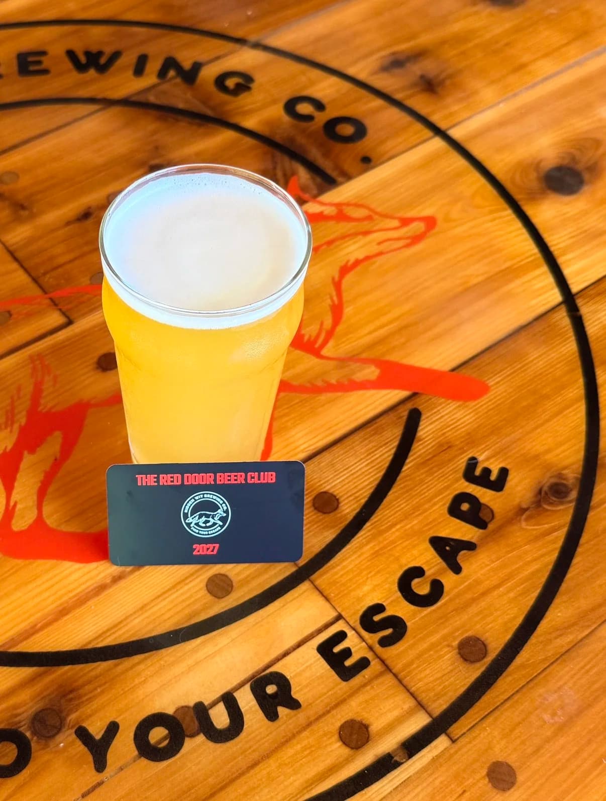 A pint of beer and Red Door Beer Club membership card on a wooden table